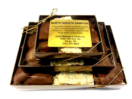 A gift box containing assorted chocolates, including sunflower seeds and potato chips, labeled "North Dakota Sampler."