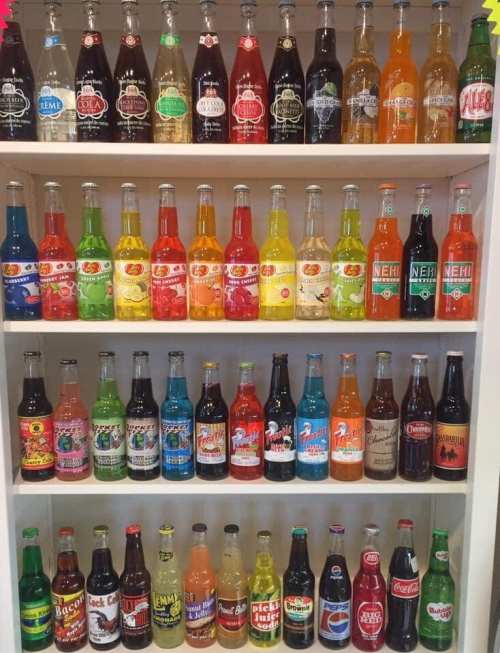 A colorful display of various soda bottles arranged on shelves, showcasing a variety of flavors and brands.