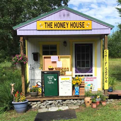 A charming roadside market called "The Honey House," featuring a colorful exterior and self-serve options.