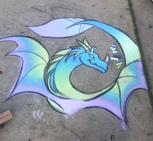 Colorful chalk drawing of a dragon with blue and green hues, surrounded by pastel chalk pieces on a concrete surface.