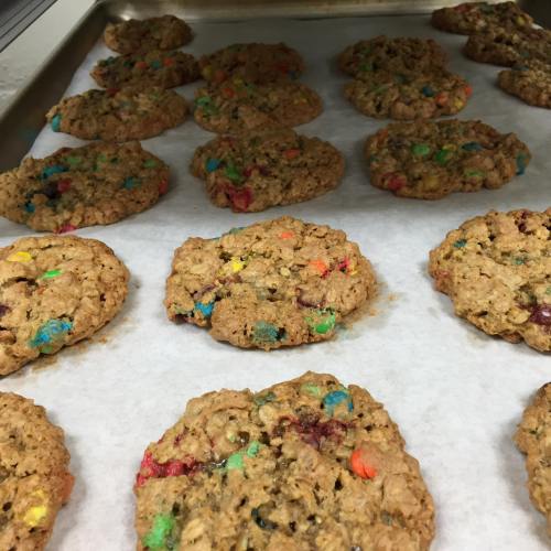 Baking tray with freshly baked oatmeal cookies studded with colorful chocolate candies.