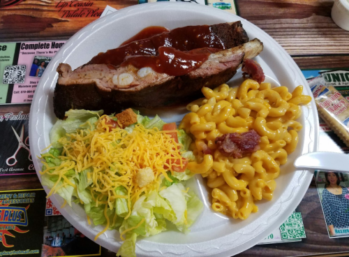 A plate with barbecue ribs, macaroni and cheese, and a side salad with lettuce, cheese, and croutons.