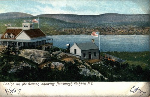 Vintage postcard depicting a casino on Mt. Beacon with views of Newburgh and Fishkill, NY, and flags waving.