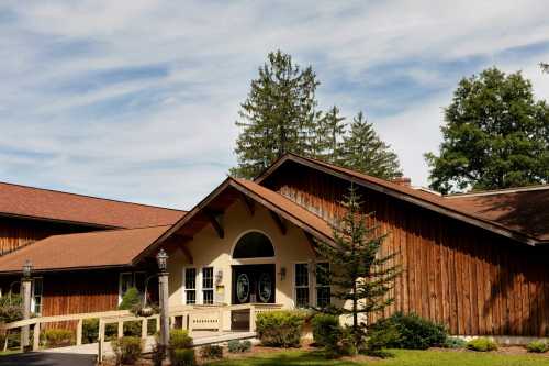 A rustic building with a wooden exterior, surrounded by trees and a clear blue sky.