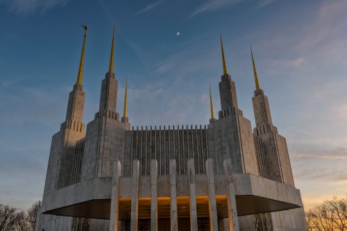 A majestic building with tall spires and a golden accent, set against a twilight sky with a crescent moon.