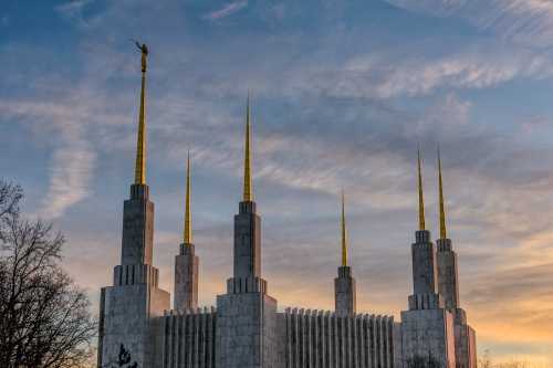 A large temple with tall, golden spires against a colorful sunset sky.