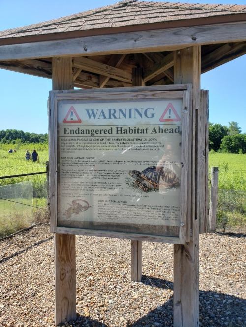 Signpost warning of endangered habitat ahead, with information about rare ecosystems and conservation efforts.