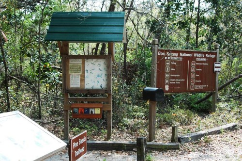 Information signs at the entrance of Bon Secour National Wildlife Refuge, surrounded by trees and nature.