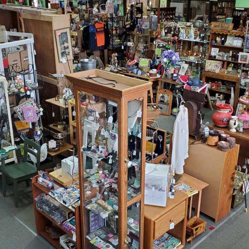 A bustling shop filled with various items, including jewelry, home decor, and clothing, displayed on shelves and tables.
