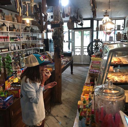 A child enjoys a treat in a vintage shop filled with candy, snacks, and various collectibles.