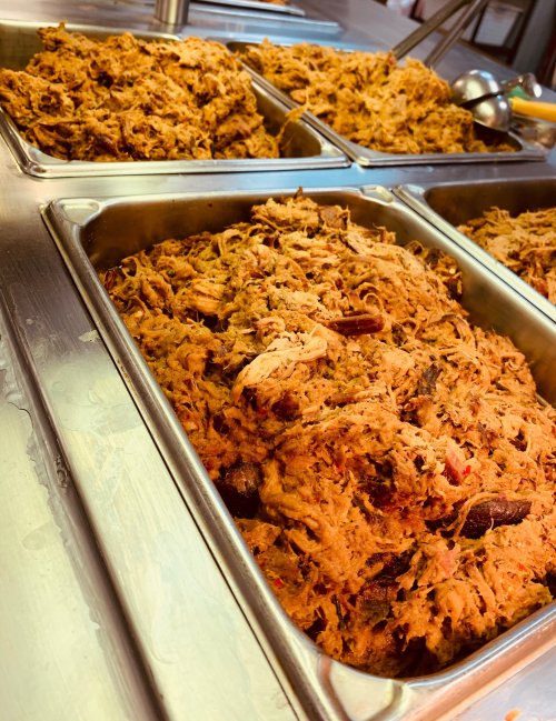 Three trays of shredded meat, seasoned and piled high, ready for serving in a food setting.