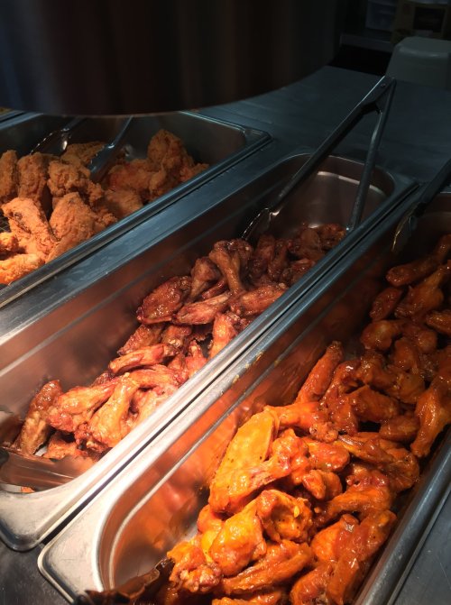 A metal tray filled with various types of chicken wings, including fried and sauced options.