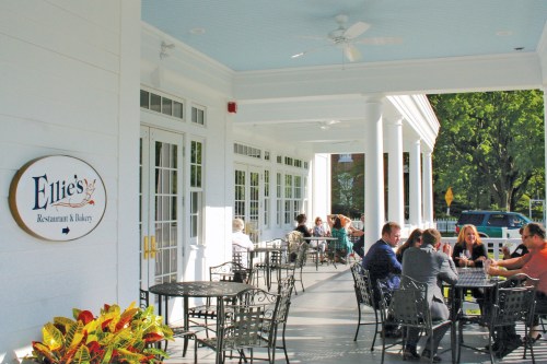 Outdoor seating area of Ellie's Restaurant & Bakery, with patrons enjoying meals at tables under a covered porch.