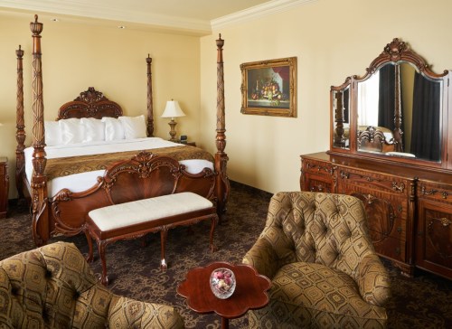 Luxurious hotel room featuring a four-poster bed, elegant furniture, and a classic decor style.