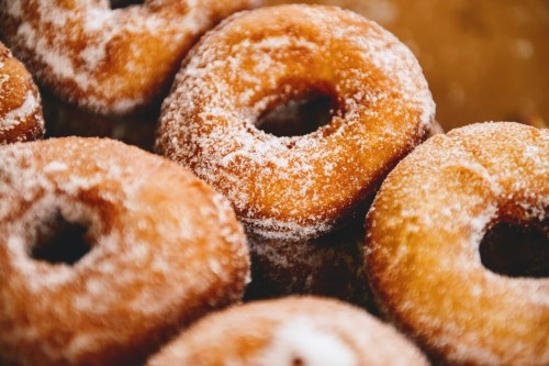 A close-up of freshly made, sugar-coated donuts arranged closely together.