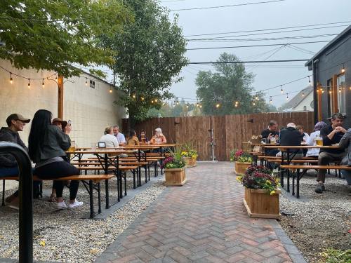 Outdoor dining area with wooden tables, string lights, and patrons enjoying their meals in a cozy atmosphere.