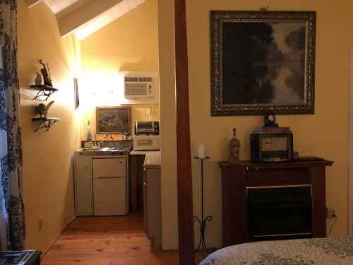 Cozy room with yellow walls, kitchenette, and a vintage-style fireplace, featuring a framed painting above.