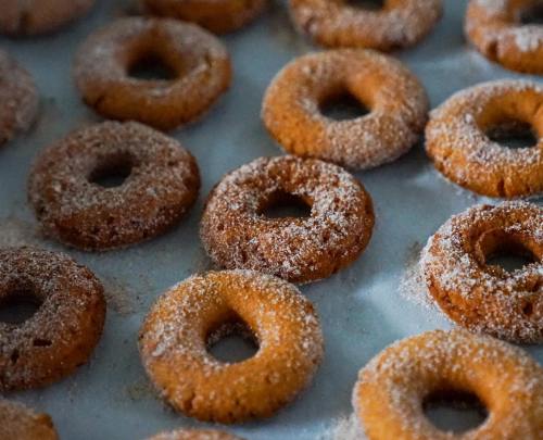 A close-up of freshly baked, sugar-coated donuts arranged on a baking sheet.