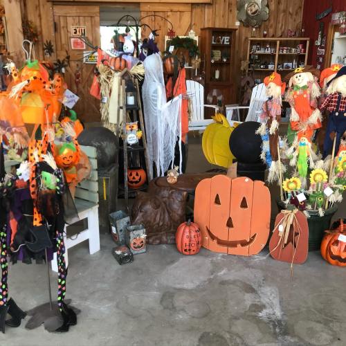 A festive display of Halloween decorations, including pumpkins, scarecrows, and colorful ornaments in a cozy shop.