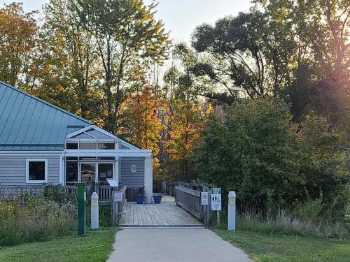 A pathway leads to a building surrounded by trees with autumn foliage, under a clear sky.