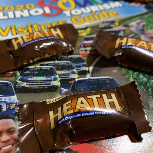 A close-up of Heath candy bars on top of a tourism guide featuring cars and wildlife.