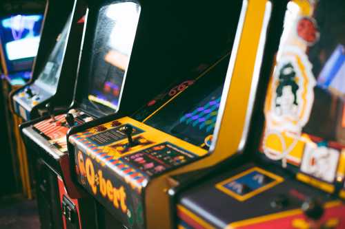 A row of vintage arcade game machines with colorful screens and retro designs.