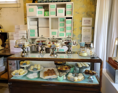 A display case filled with various desserts, including cupcakes and pastries, in a cozy bakery setting.