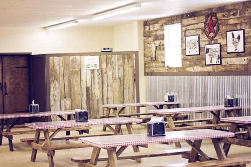 A spacious dining area with wooden picnic tables, tissue boxes, and rustic decor on the walls.