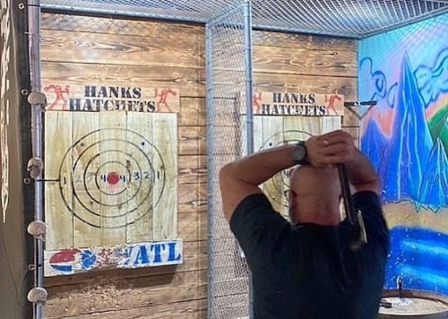 A person prepares to throw an axe at a target in an indoor axe-throwing venue.