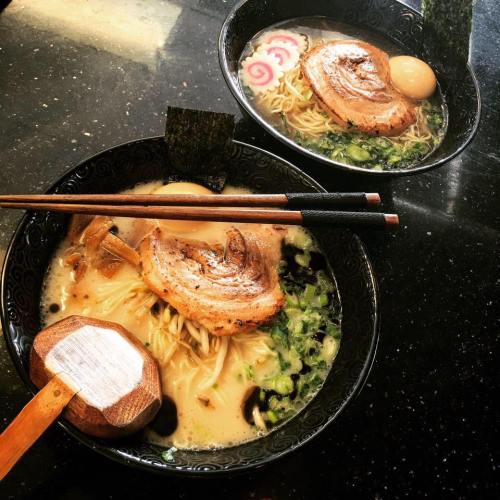 Two bowls of ramen with pork slices, noodles, green onions, and a soft-boiled egg, served with chopsticks.