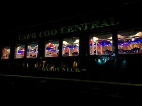 A train car at night, decorated with colorful lights and festive decor, showcasing a cozy interior.