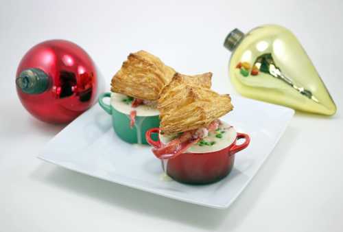 Two small pots filled with creamy soup topped with flaky pastry, surrounded by festive Christmas ornaments.