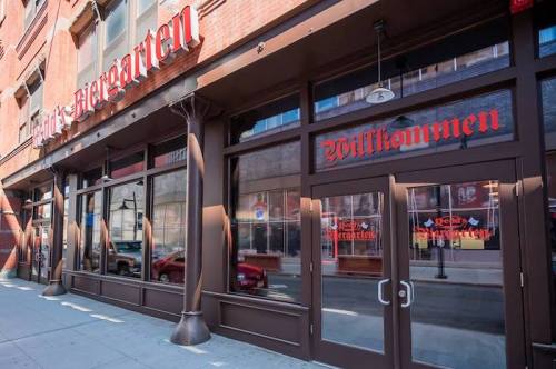 Exterior of a restaurant with large windows and a sign reading "Willkommen" in a brick building.