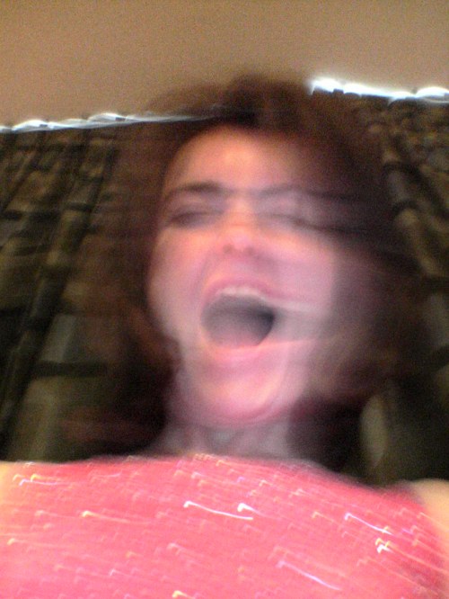 A blurred image of a person with a distorted face, appearing to scream or express intense emotion.