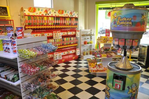 A colorful candy store featuring shelves of sweets, a Pickle Powder dispenser, and a checkered floor.