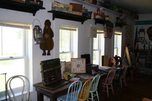 A cozy room with vintage toys, a lantern, and colorful chairs arranged around wooden tables by sunny windows.