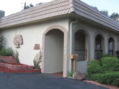 A building with a sloped roof, arched entryway, and a sign displaying the number 888, surrounded by greenery.