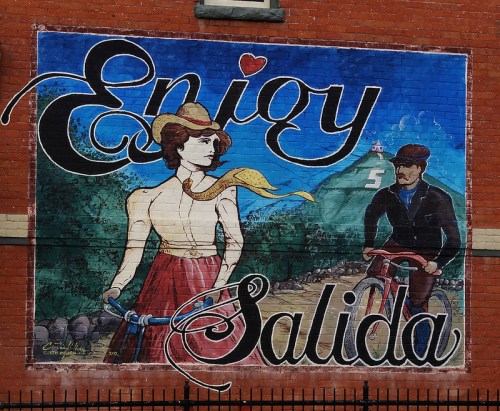 A colorful mural featuring a woman in a cowboy hat and a man on a bicycle, with the words "Enjoy Salida."