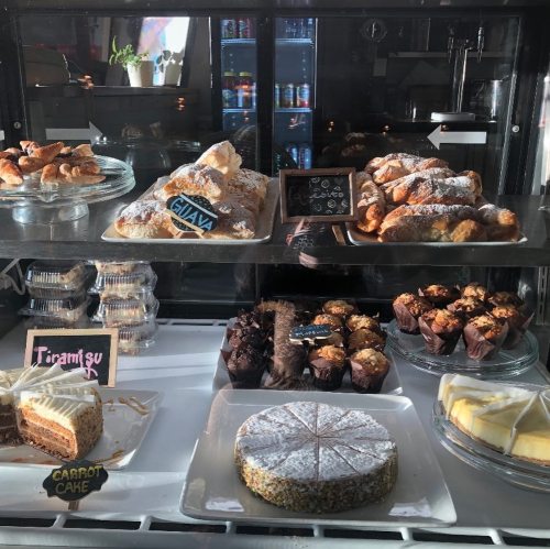 A display case filled with various baked goods, including pastries, cakes, and muffins, all beautifully arranged.