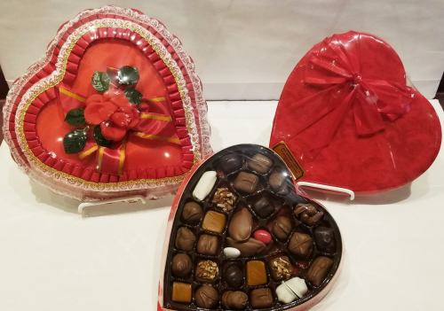 Three heart-shaped boxes of chocolates, one with a floral design and two filled with assorted chocolates.