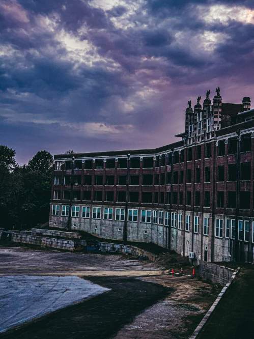 Abandoned building with a curved facade under a moody sky, surrounded by a barren landscape.