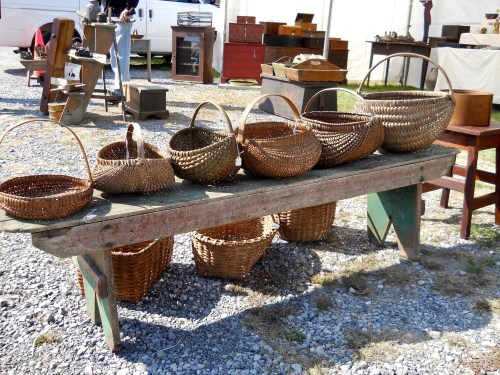 A row of woven baskets of various sizes displayed on a rustic wooden table at an outdoor market.