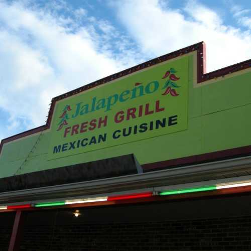 Sign for Jalapeño Mexican Grill, featuring bright colors and a clear sky in the background.