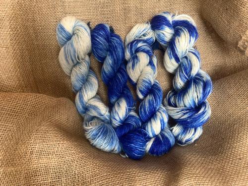 Three skeins of blue and white yarn arranged on a textured burlap background.