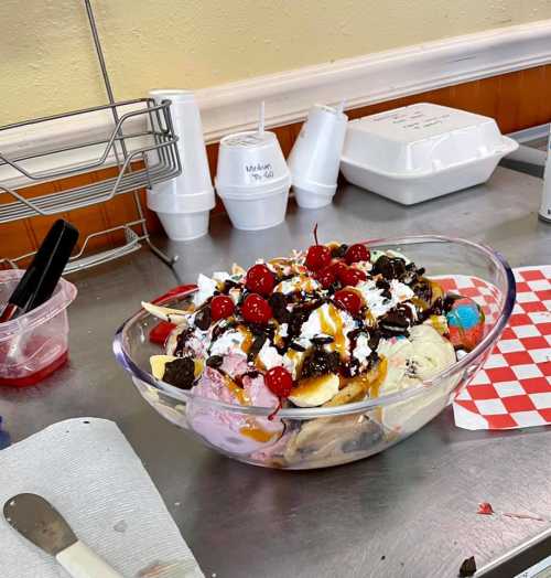 A large ice cream sundae in a bowl, topped with whipped cream, cherries, chocolate syrup, and various toppings.