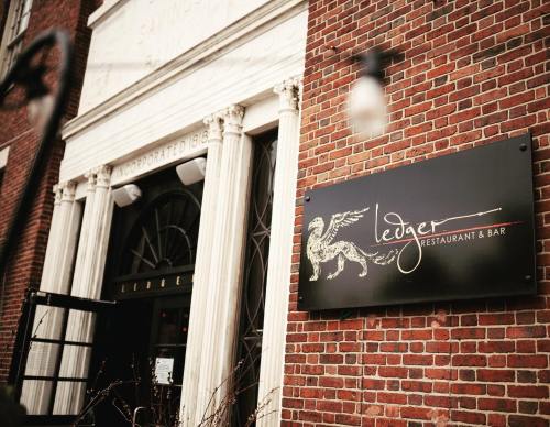 Exterior of Ledger Restaurant & Bar, featuring a brick facade and a sign with a golden griffin logo.