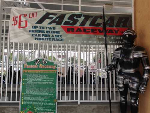 A knight statue stands beside a banner advertising $6 races for two riders at Fastcar Raceway.