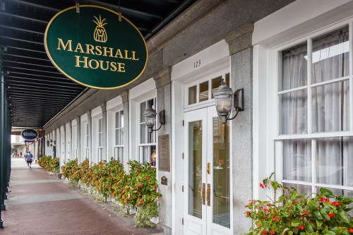 Exterior of the Marshall House with a sign, featuring flower boxes along the windows and a brick walkway.
