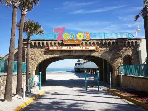 Archway entrance to Zeno's, with a beach view and palm trees, featuring a sign that reads "World's Most Famous Taffy."