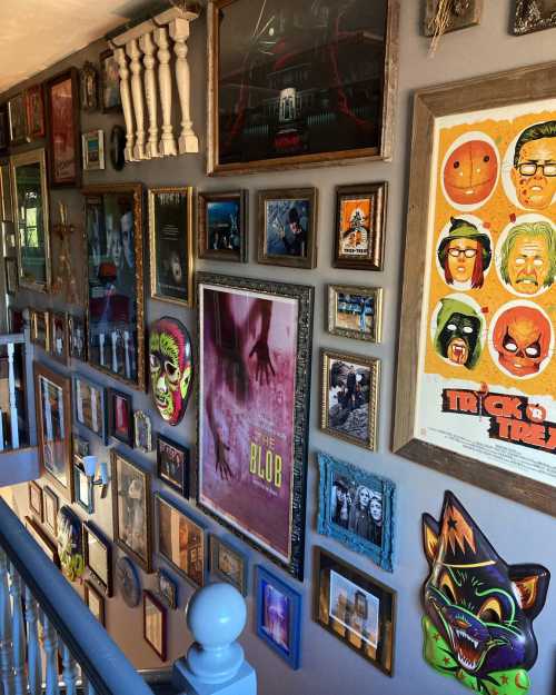 A staircase wall adorned with a variety of framed artwork, including movie posters and colorful masks.